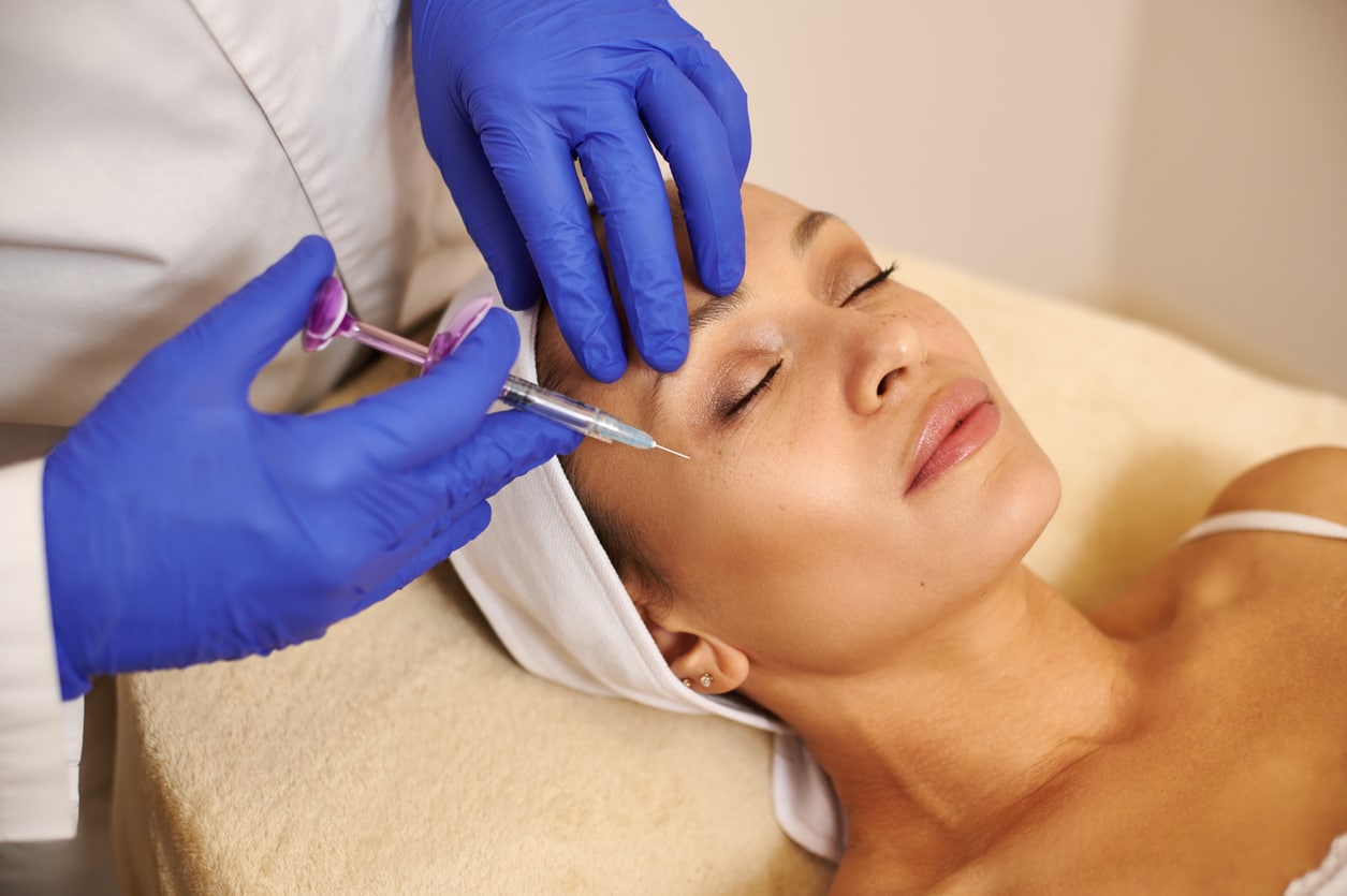 Doctor making beauty injections into a woman's face.